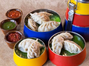 On propose une variété de raviolis servis dans des bols colorés, accompagnés de différentes sauces.