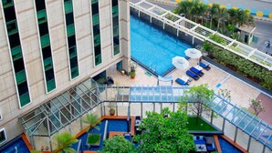 A rooftop pool area with lounge chairs, a glass balustrade, and a view of the building's interior. - Ibis Bengaluru Outer Ring Road (Bengaluru)