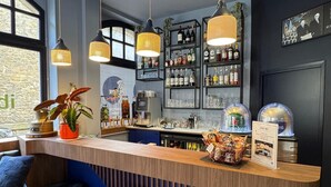 A bar area with a wooden counter, black stools, and hanging pendant lights. - ibis Styles Saint-Malo Centre Historique (Saint-Malo)