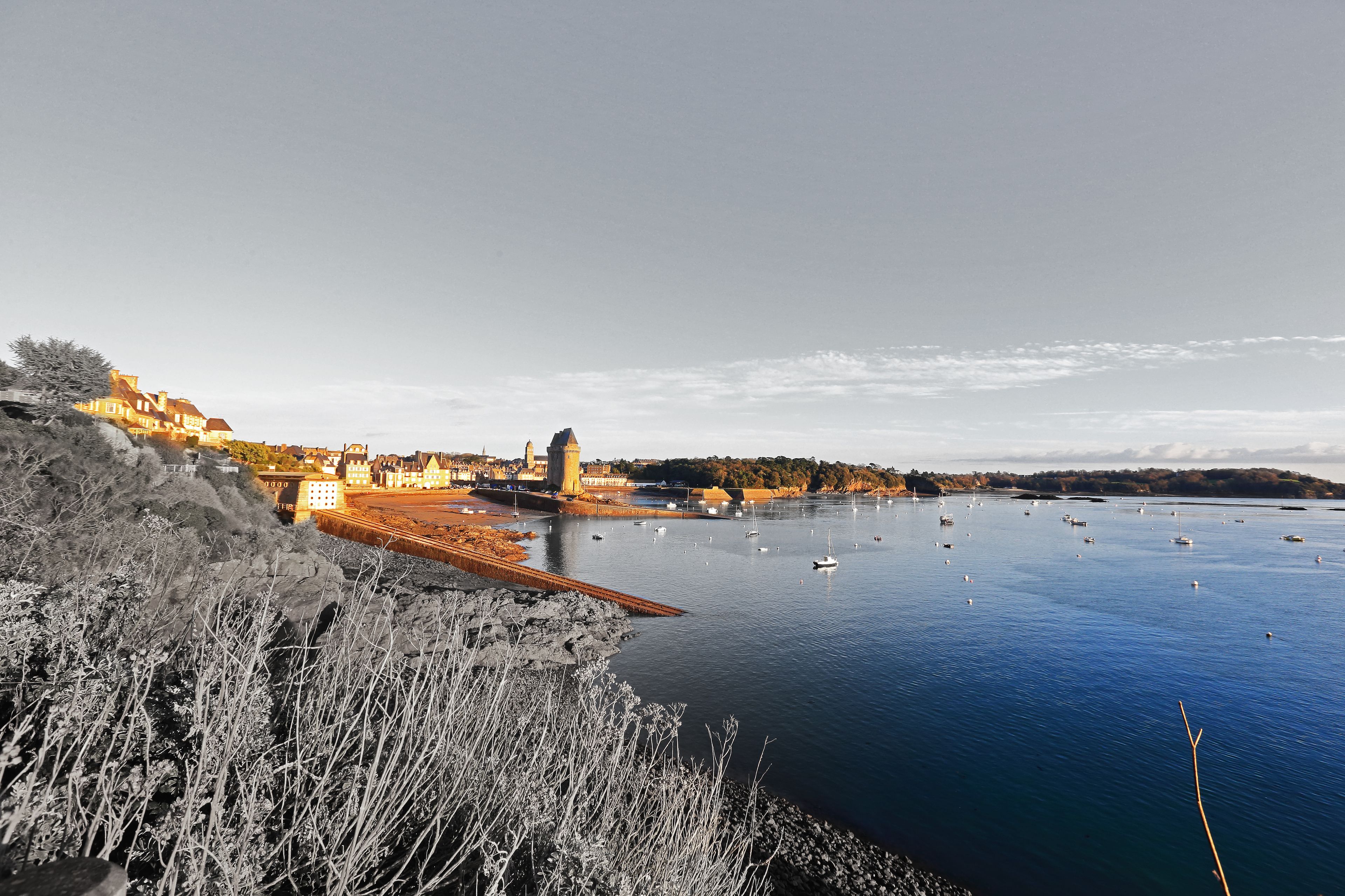 A coastal town with a harbor, boats, and buildings along the shore.