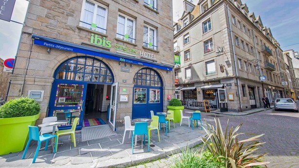 A hotel with a blue entrance, outdoor seating, and a cobblestone street. - ibis Styles Saint-Malo Centre Historique (Saint-Malo)