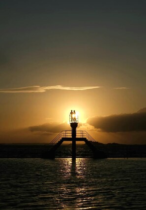 Un molo che si protende su un corpo d'acqua, con un tramonto sullo sfondo.