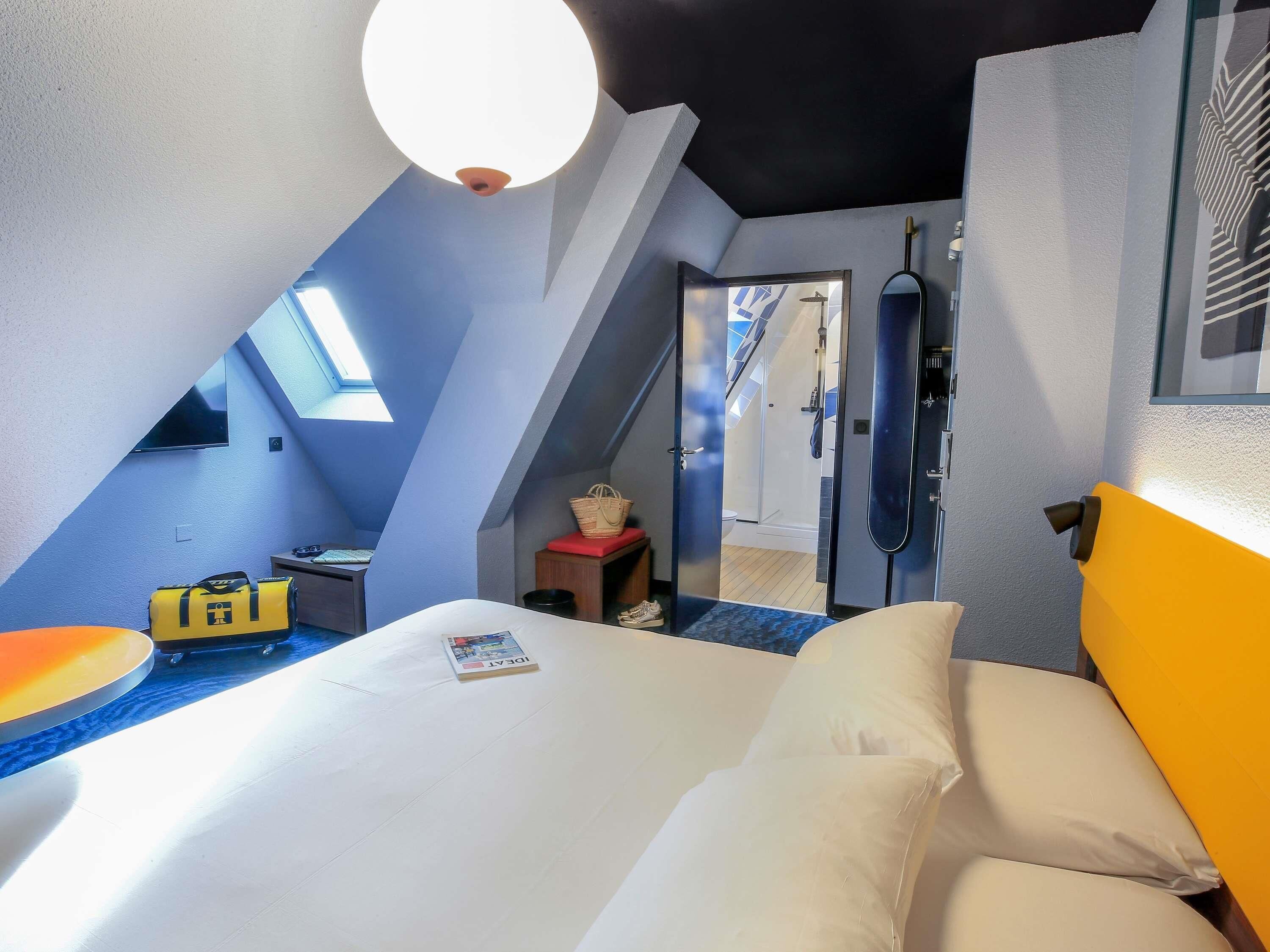 A room with a bed, a desk, a chair, a lamp, and a window.