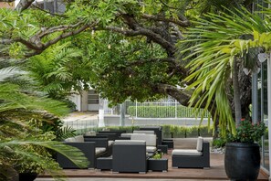 An outdoor seating area with wicker furniture and potted plants. - NH Collection Barranquilla Smartsuites Royal (Barranquilla)