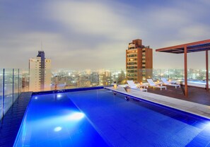 A rooftop pool with lounge chairs and a city view. - NH Collection Barranquilla Smartsuites Royal (Barranquilla)