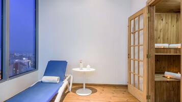 Relax in a serene space with a comfortable lounge chair, a small table, and a bed through a wooden door.