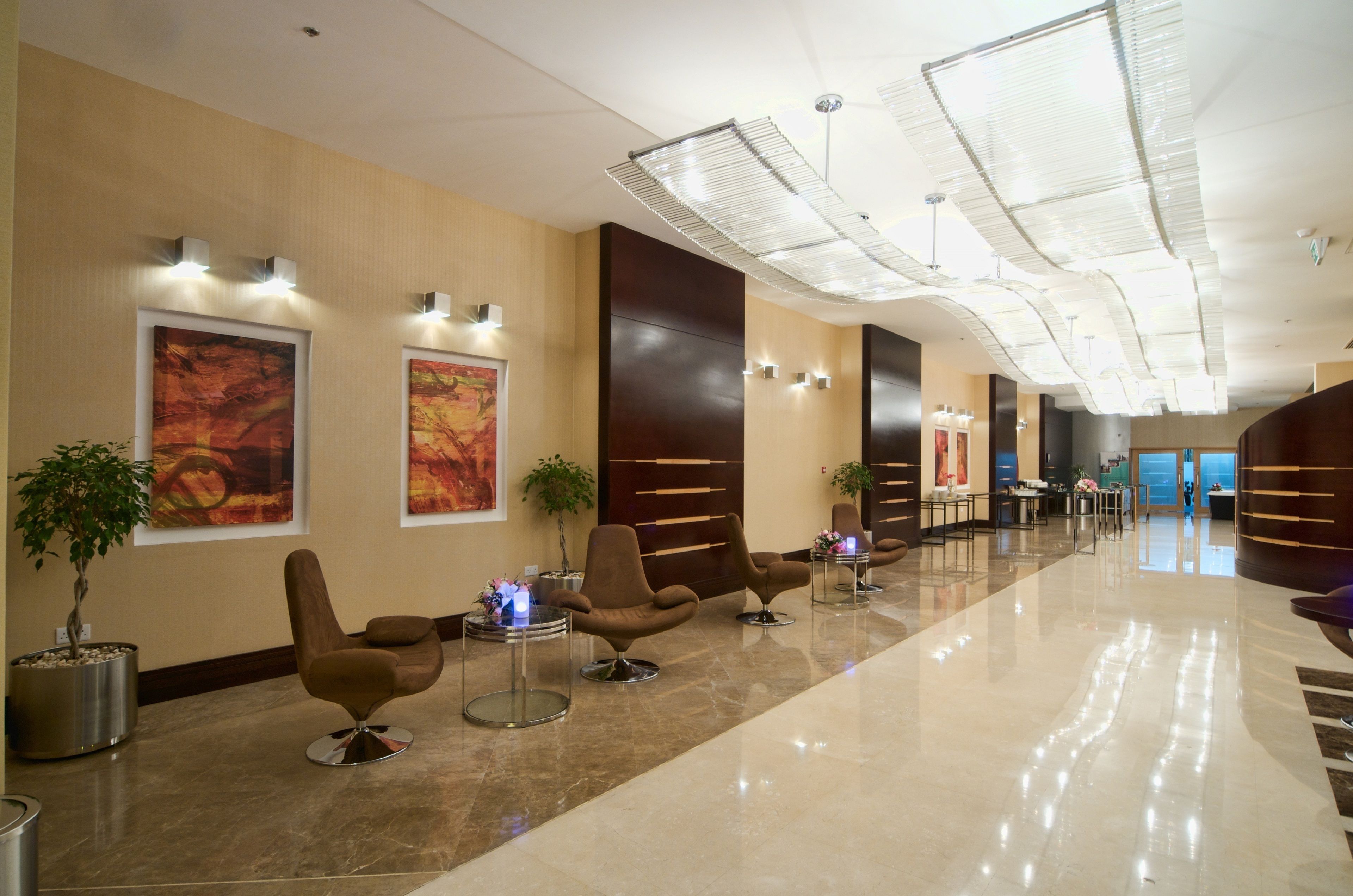 Un moderno vestíbulo de hotel con un mostrador de recepción alargado, zonas de estar cómodas y obras de arte en las paredes.