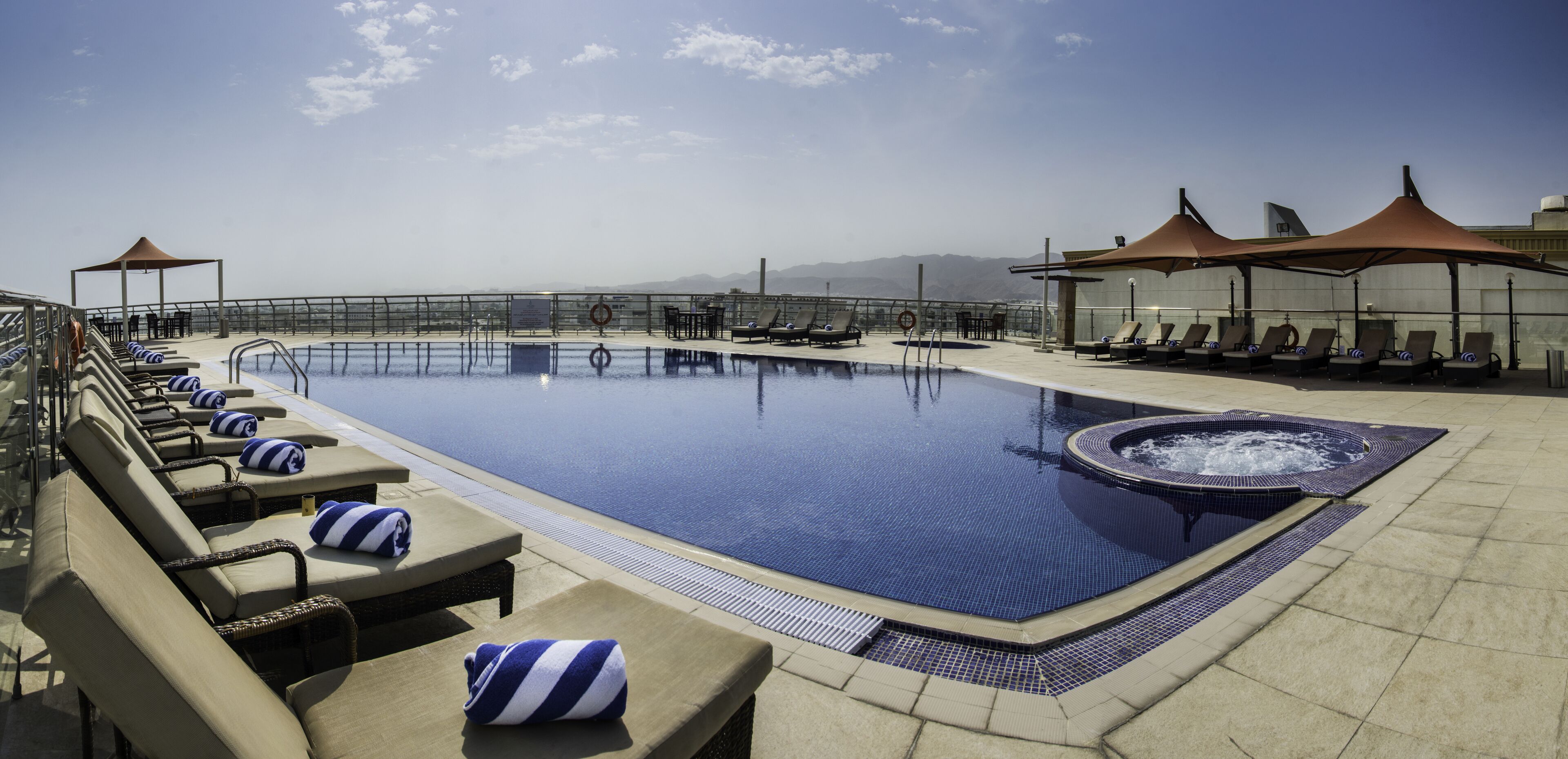 Una piscina al aire libre, sombrillas, sillones reclinables de piscina