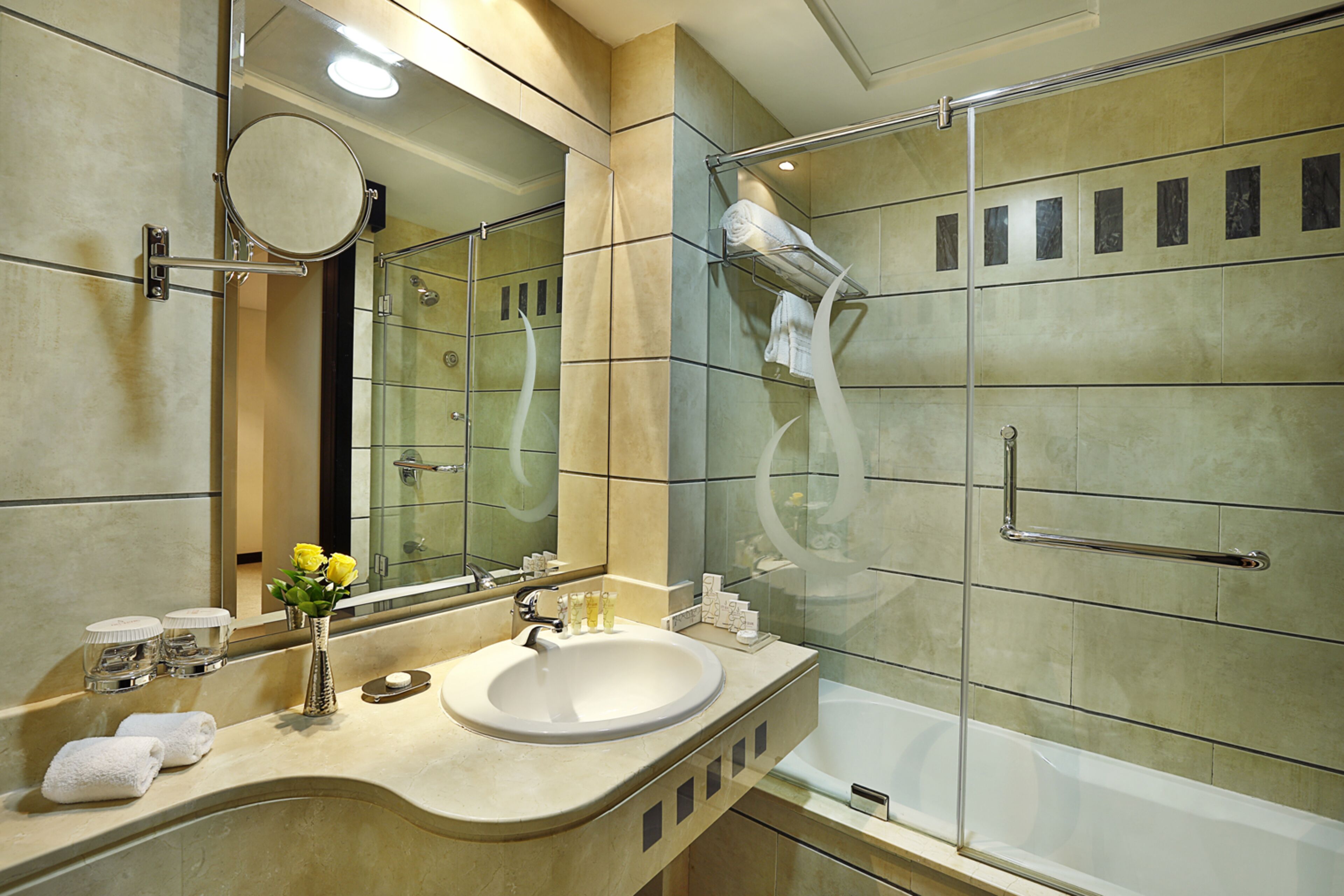 A modern bathroom with a large mirror, a sink, and a glass-enclosed shower area.