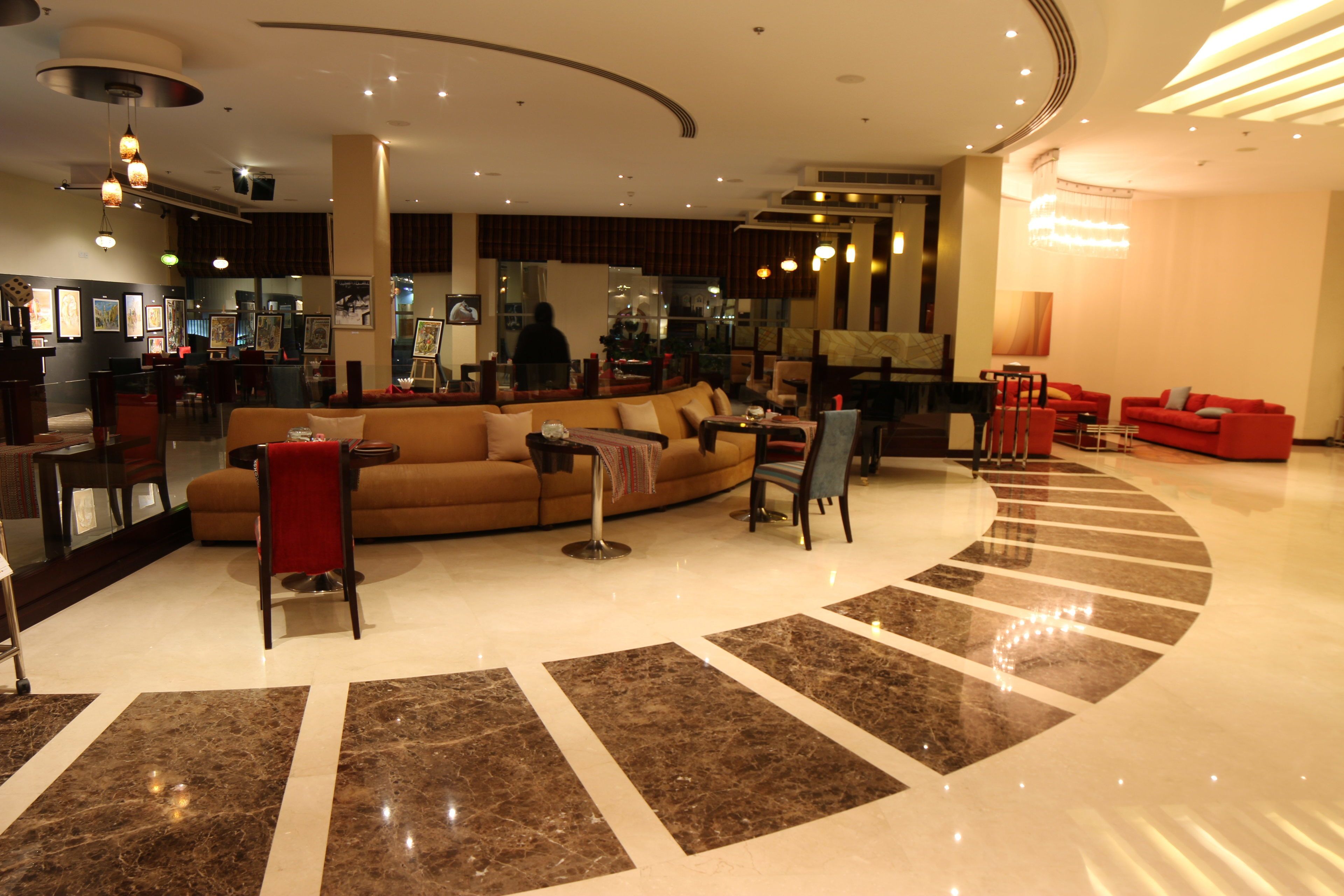 A spacious lobby with a curved seating area, a dining section, and a modern chandelier.