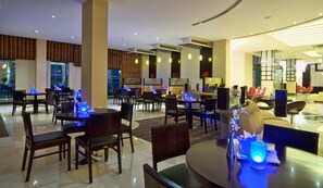 A modern hotel lobby with multiple dining areas, some with blue ambient lighting. - City Seasons Hotel Muscat (Muscat)