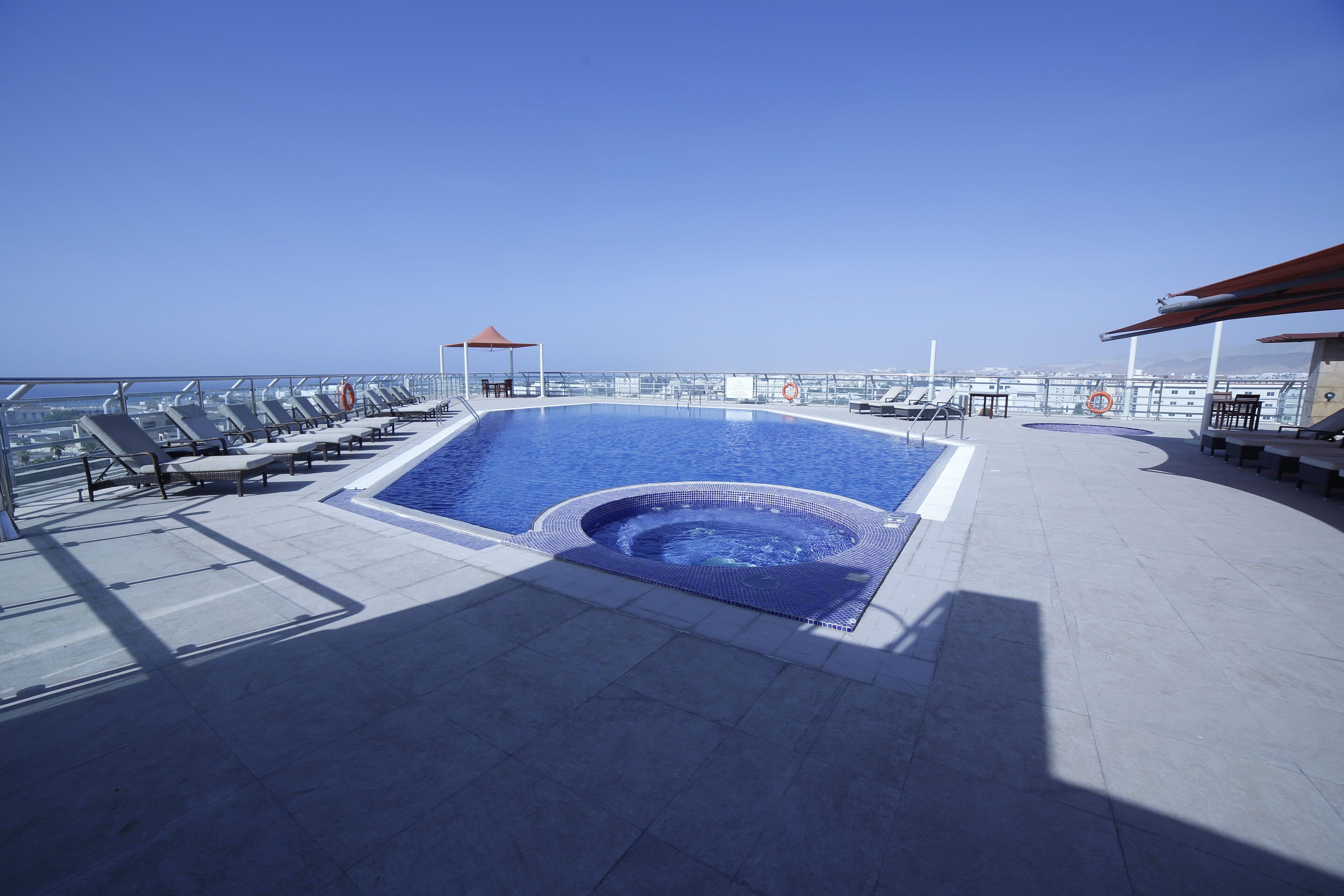 Ein Pool auf dem Dach mit Liegestühlen, einem Whirlpool und freiem Blick auf das Meer.