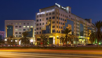 A multi-story hotel with a prominent "City Seasons Hotel" sign, featuring a modern architectural design with large windows and a central atrium.