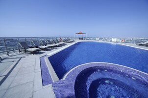A rooftop pool with lounge chairs and a small gazebo.