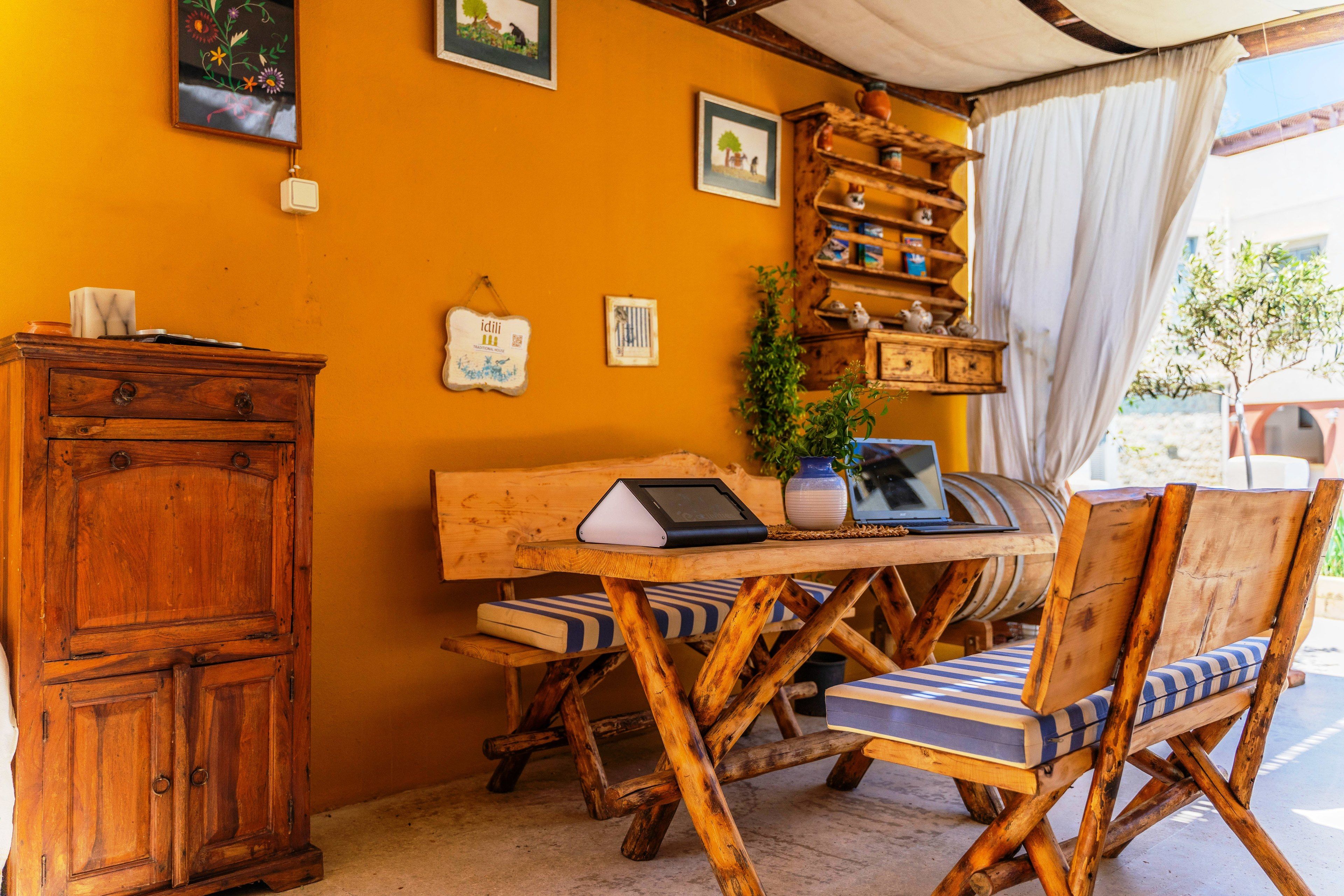 A rustic wooden table with a laptop, a potted plant, and a shelf with decorative items.