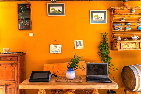 A wooden table with two laptops, a vase with a plant, and a wooden cabinet with decorative items.