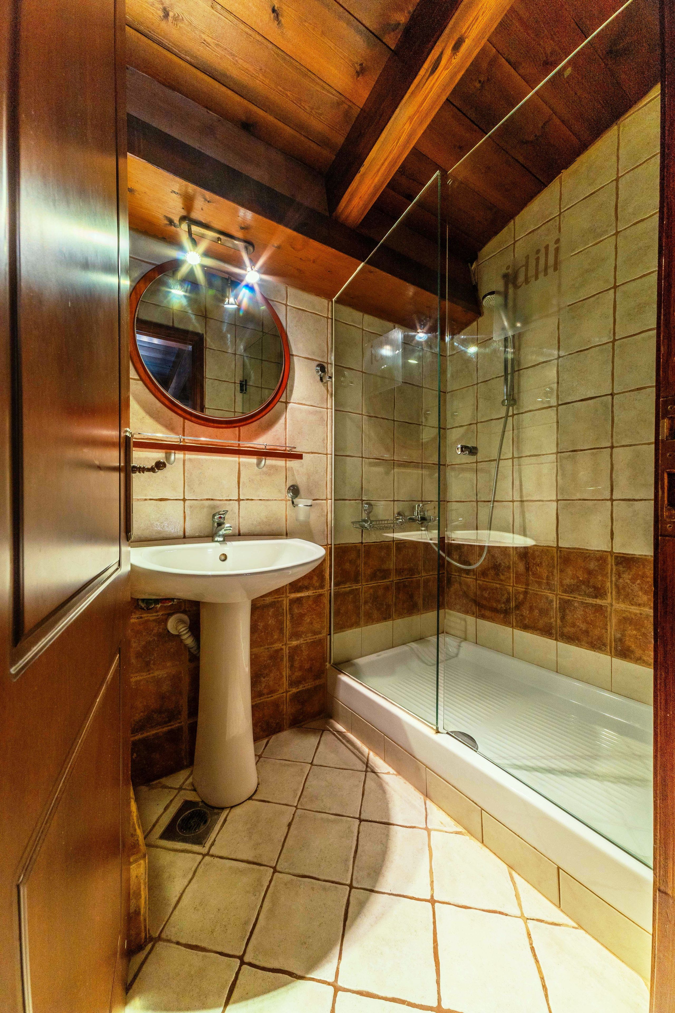 A bathroom with a sink, mirror, and glass-enclosed shower.