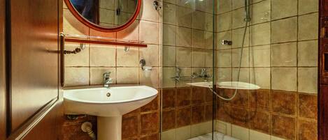 A bathroom with a sink, mirror, and glass-enclosed shower.