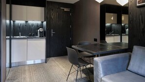 A modern kitchen with dark wood cabinetry, a built-in coffee machine, and a large dining table with chairs. - Four Points Flex by Sheraton Birmingham Jewellery Quarter (Birmingham)