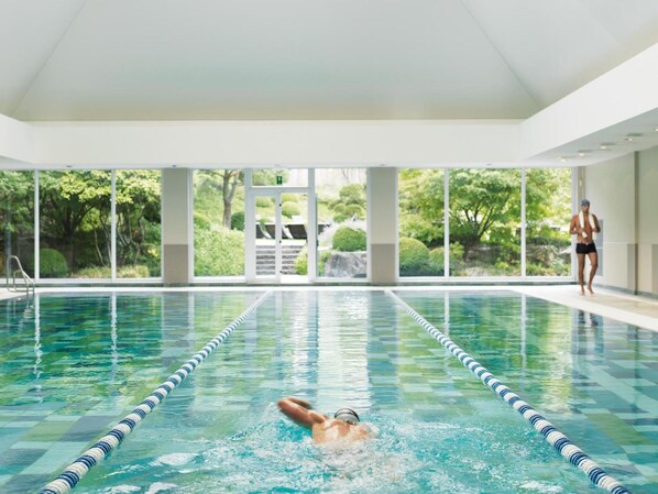A swimming pool with clear water, lane dividers, and a person swimming.