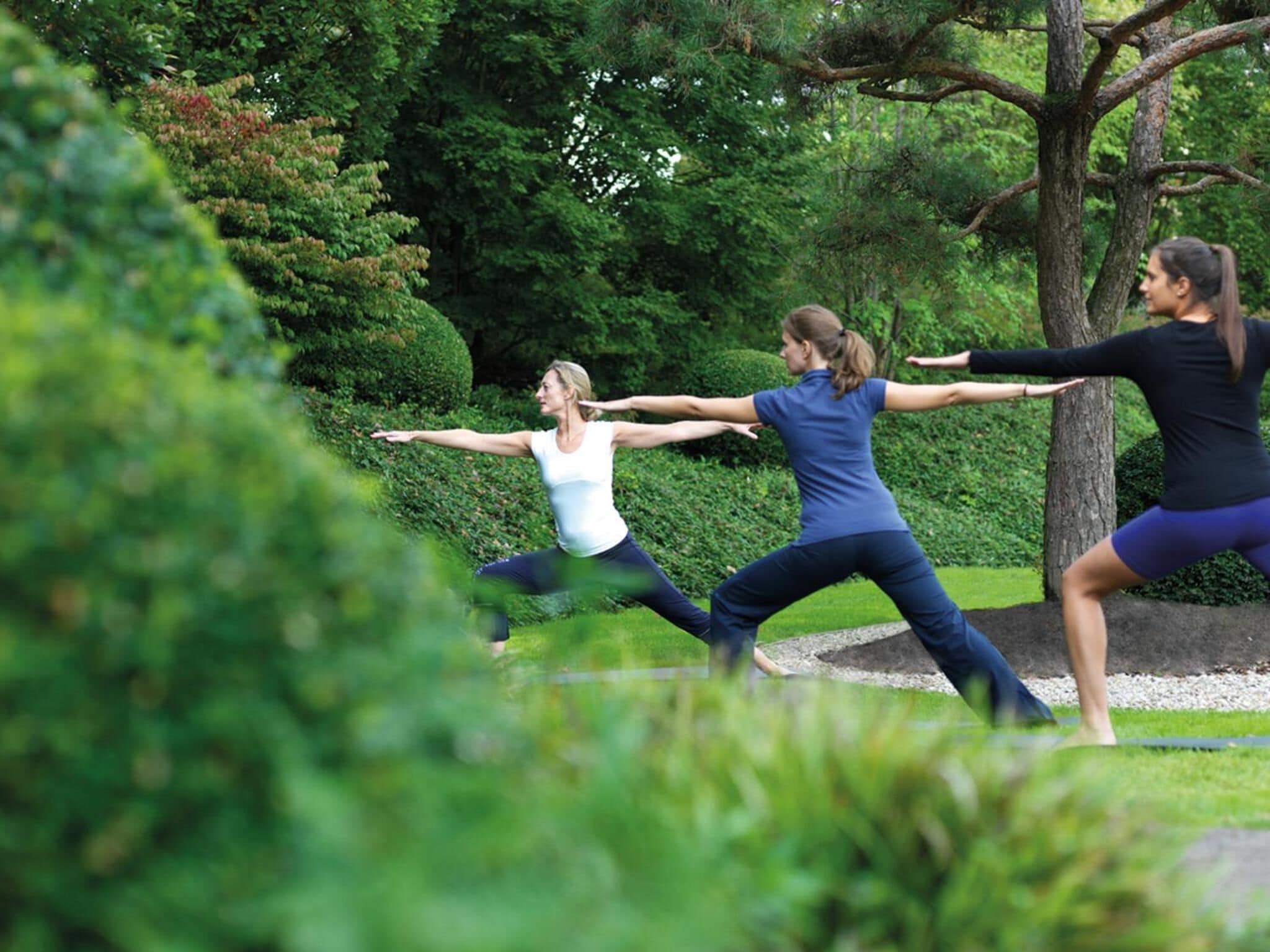 Three people performing a yoga pose outdoors.