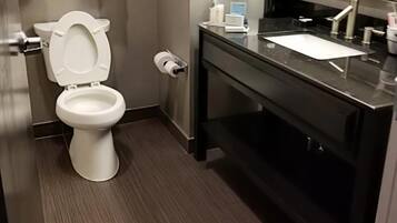 A modern bathroom with a white toilet, a black sink, and a mirror above the sink.