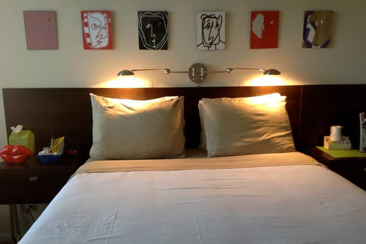 Una habitación de hotel con una cama grande, dos lámparas de noche y decoración en la pared.