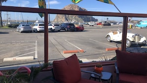 A view from a window overlooking a parking lot with several cars, a vintage car, and a mountain in the background.