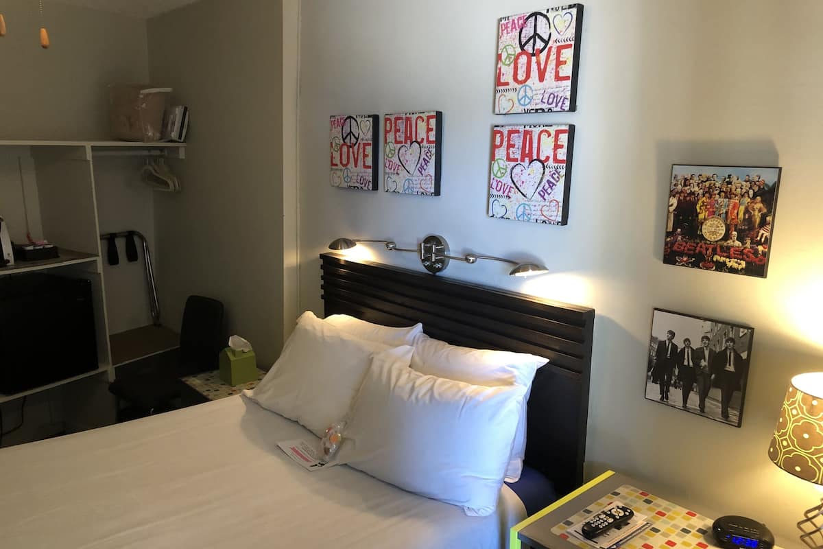 Una habitación de hotel con cama, mesita de noche, lámpara y decoración en la pared.