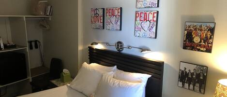 Una habitación de hotel con cama, mesita de noche, lámpara y decoración en la pared.