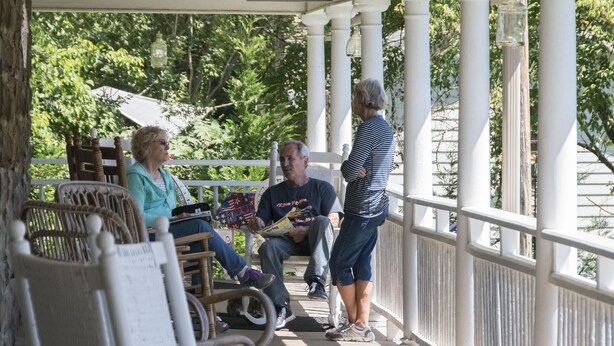Eine Veranda mit weißen Säulen, Korbstühlen und einem Schild mit der Aufschrift 'MOVIE GALLERY'.