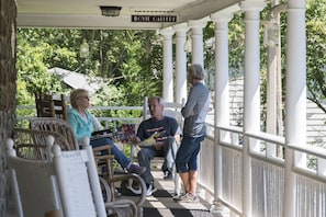 A porch with white columns, wicker chairs, and a sign reading "MOVIE GALLERY". - Calhoun House Inn & Suites (Bryson City)