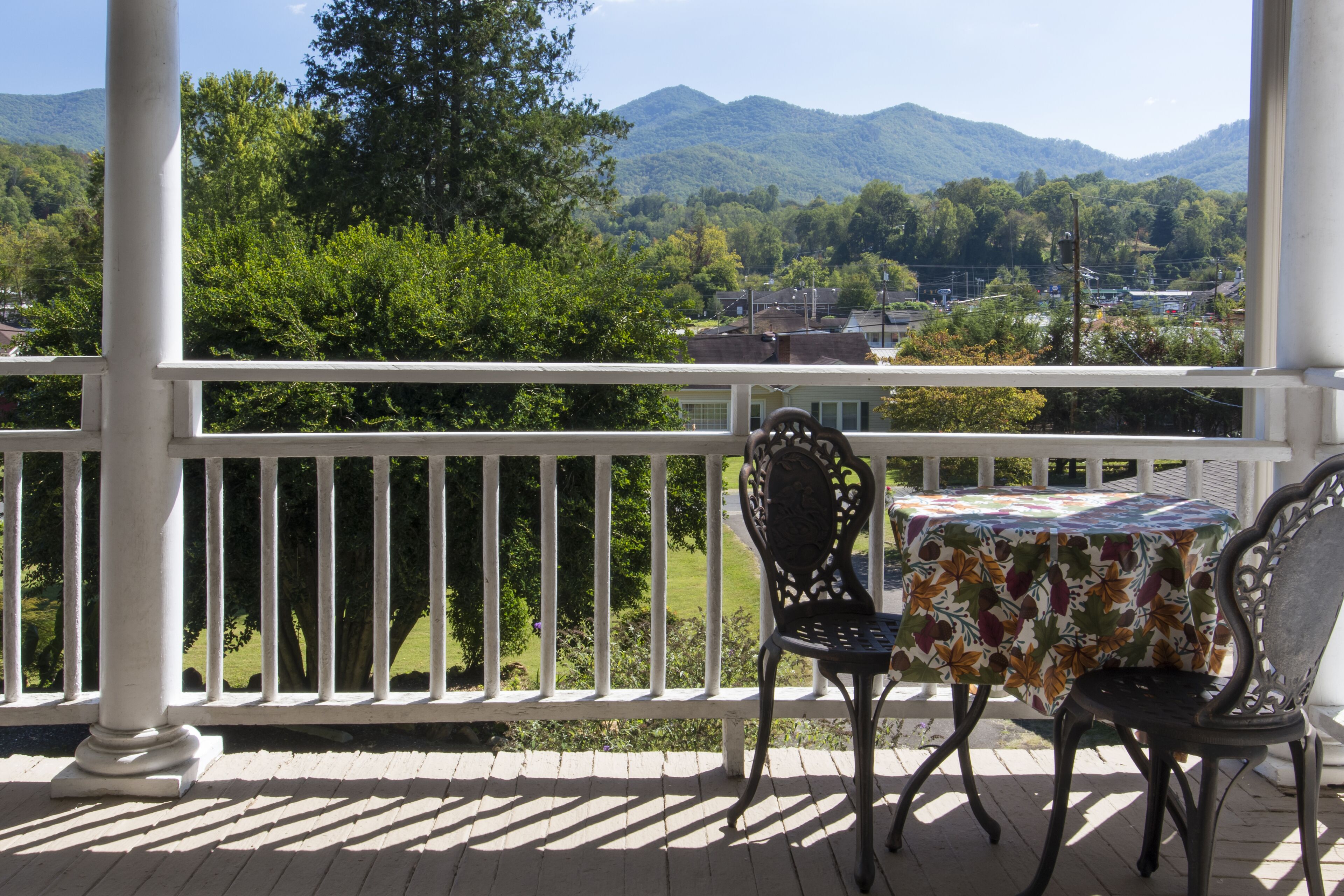 Ein überdachter Außenbereich mit Tisch und zwei Stühlen, mit Blick auf eine Berglandschaft.