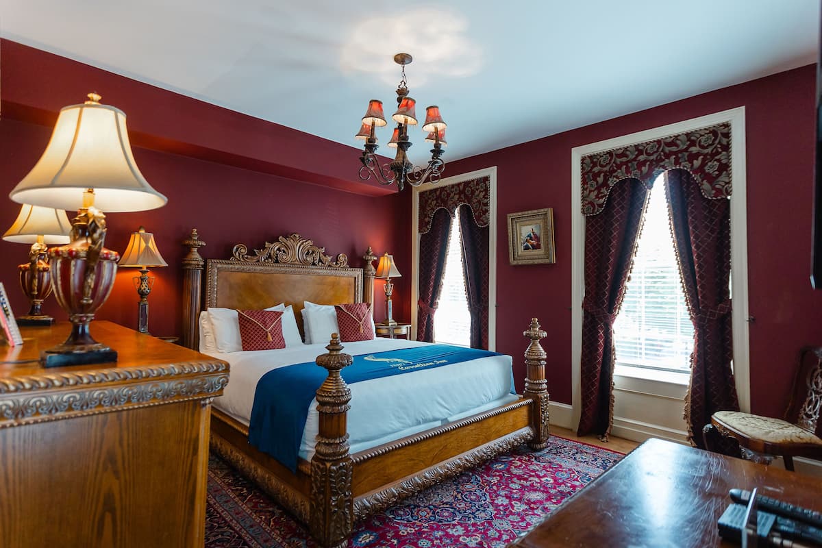 A traditional room with a four-poster bed, ornate headboard, and a chandelier.