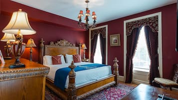 A traditional room with a four-poster bed, ornate headboard, and a chandelier.