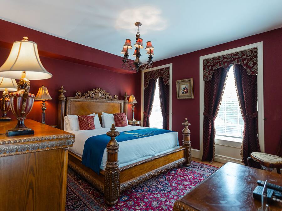 A traditional room with a four-poster bed, ornate headboard, and a chandelier.