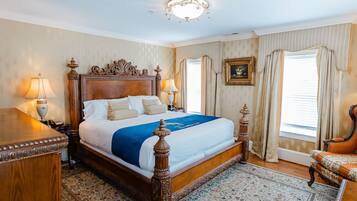 A large, ornate bed with a wooden headboard, two bedside lamps, and a blue bedspread.
