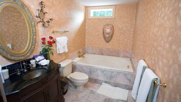 A bathroom with a large ornate mirror, a bathtub, a toilet, and a sink.
