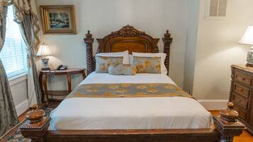 A neatly made bed with floral bedding, a wooden headboard, and a bedside table with a lamp.