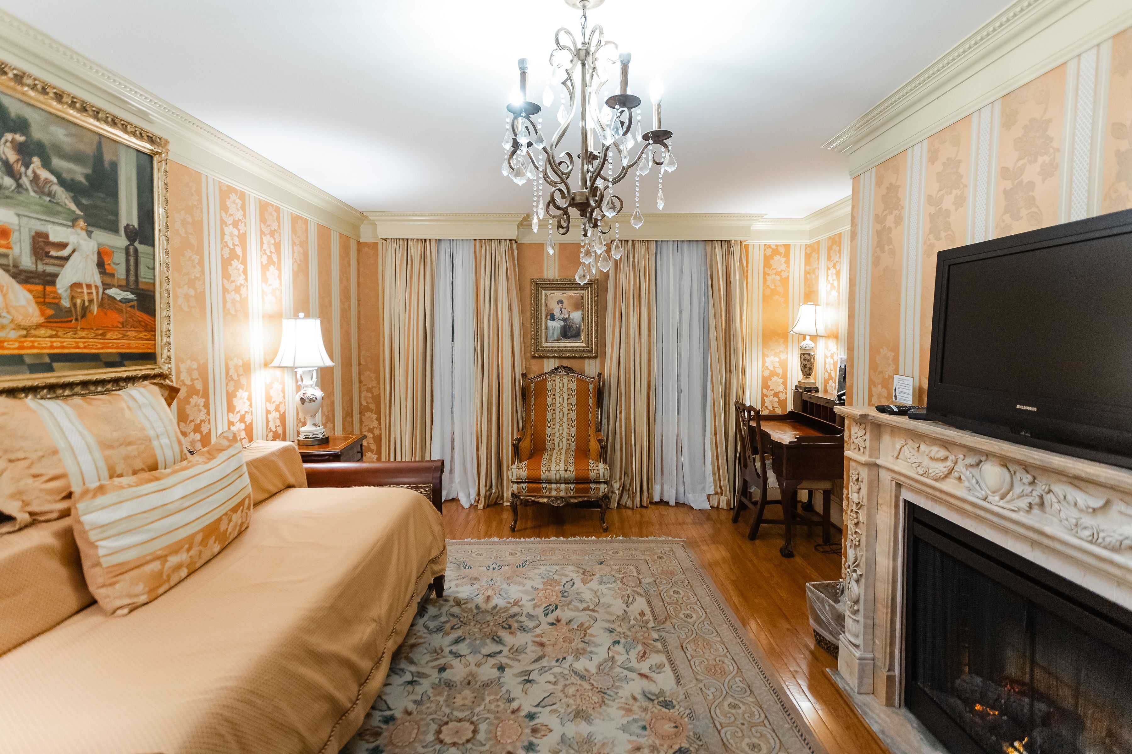 A well-appointed hotel room with a large bed, a fireplace, a television, and a chandelier.