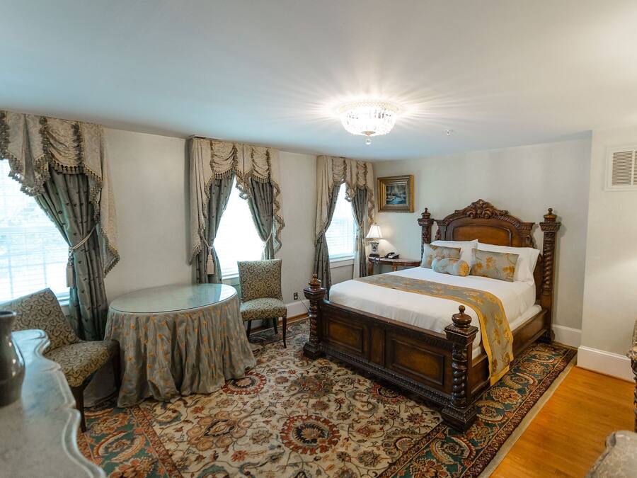 A traditional bedroom with a large bed, a round table, and a patterned carpet.
