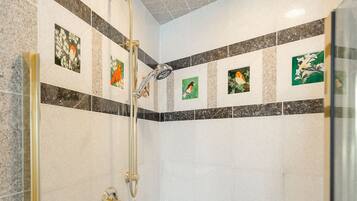 A modern shower area with a glass door, a handheld showerhead, and a handheld shower attachment.