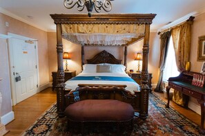 Un lit à baldaquin, un banc en bois, un piano et un tapis à motifs.