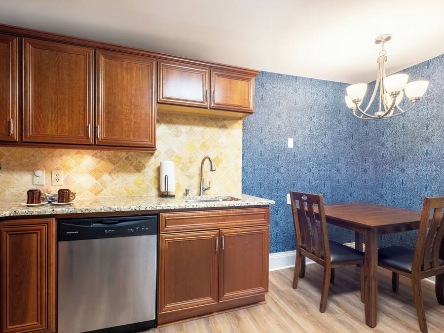 A kitchen with wooden cabinets, a dishwasher, a sink, and a dining table with chairs.
