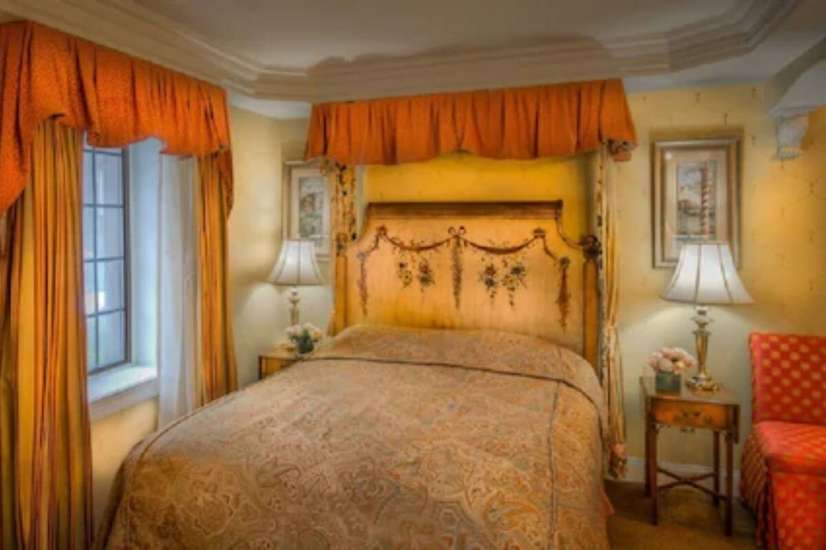 A classic bedroom with a large bed, ornate headboard, and curtains.