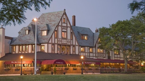 A traditional Tudor-style building with multiple dining areas, each with a red awning and outdoor seating. - Red Coach Inn (Niagara Falls)