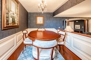 A dining room with a wooden table and chairs, a chandelier, and a patterned rug. - Red Coach Inn (Niagara Falls)