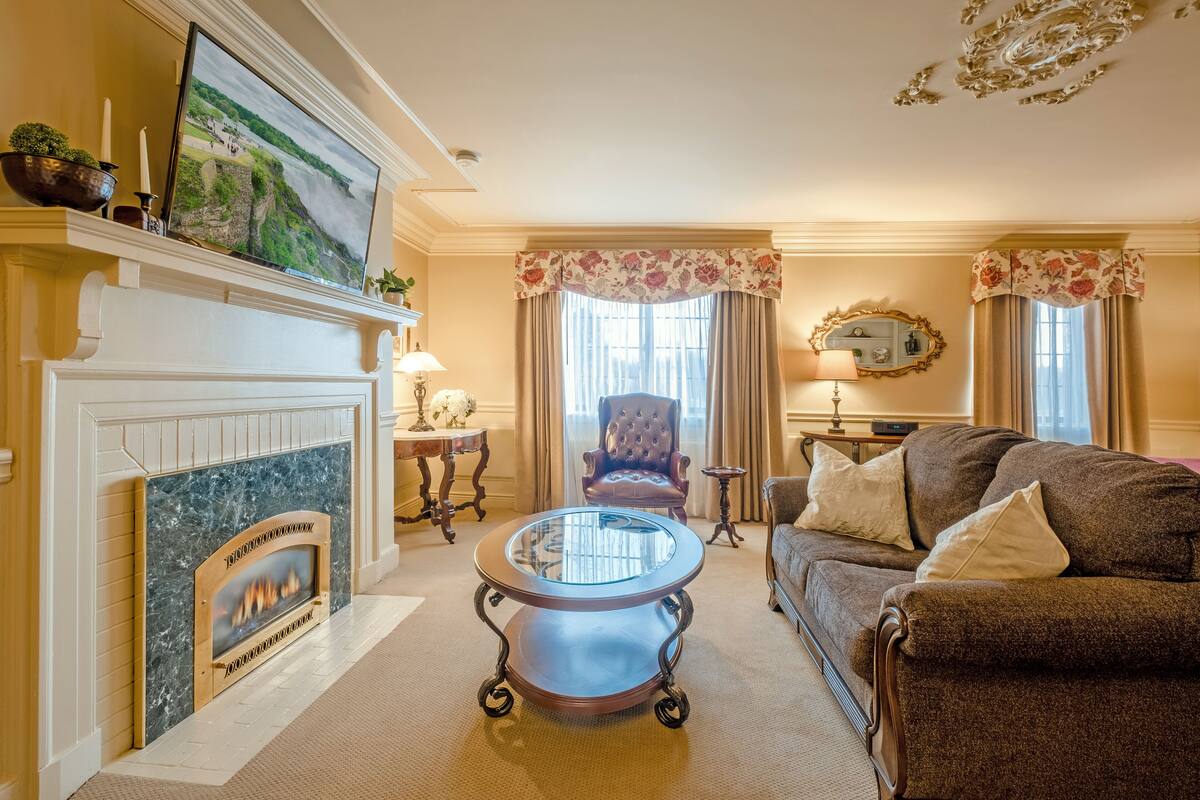 A living room with a fireplace, a round glass coffee table, a sofa, and a chair.