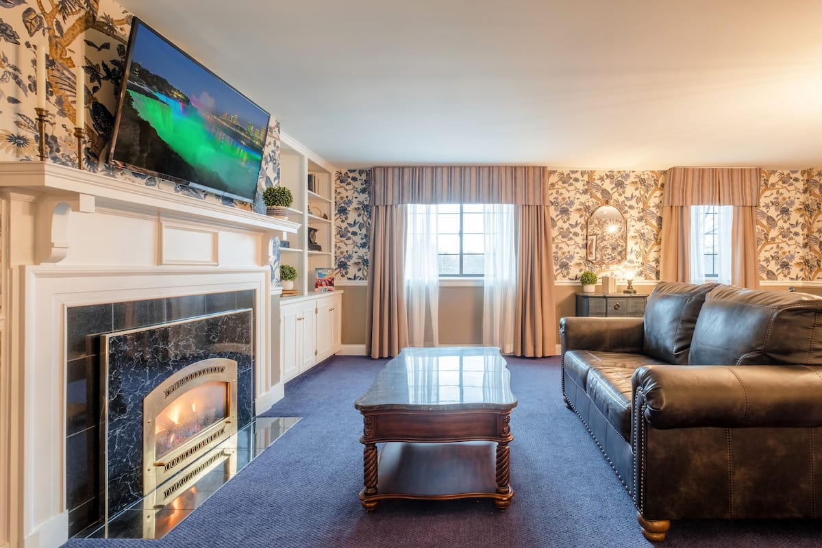 A living room with a fireplace, a television, a leather sofa, and a coffee table.