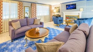 A living room with a purple sofa, a blue patterned rug, and a fireplace. - Red Coach Inn (Niagara Falls)